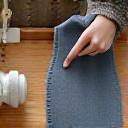 Hånd som klipper mønster i et stoff med skreddersaks og tråd